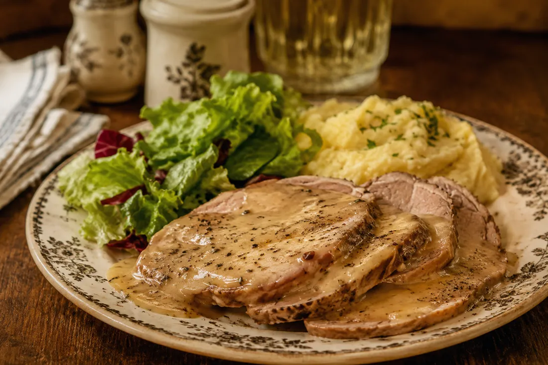 Sliced roast veal in a caraway and sour cream pan sauce, plated with salad and puree